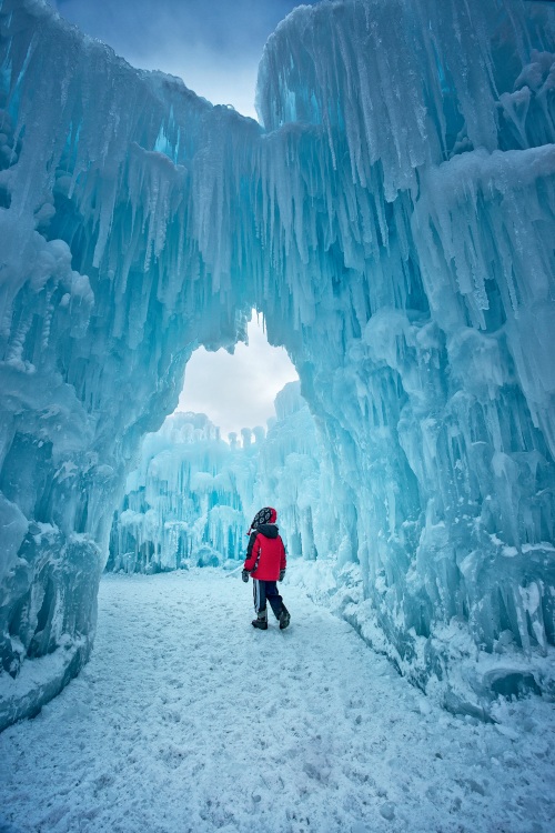 Small child walks under ice arch, photo
