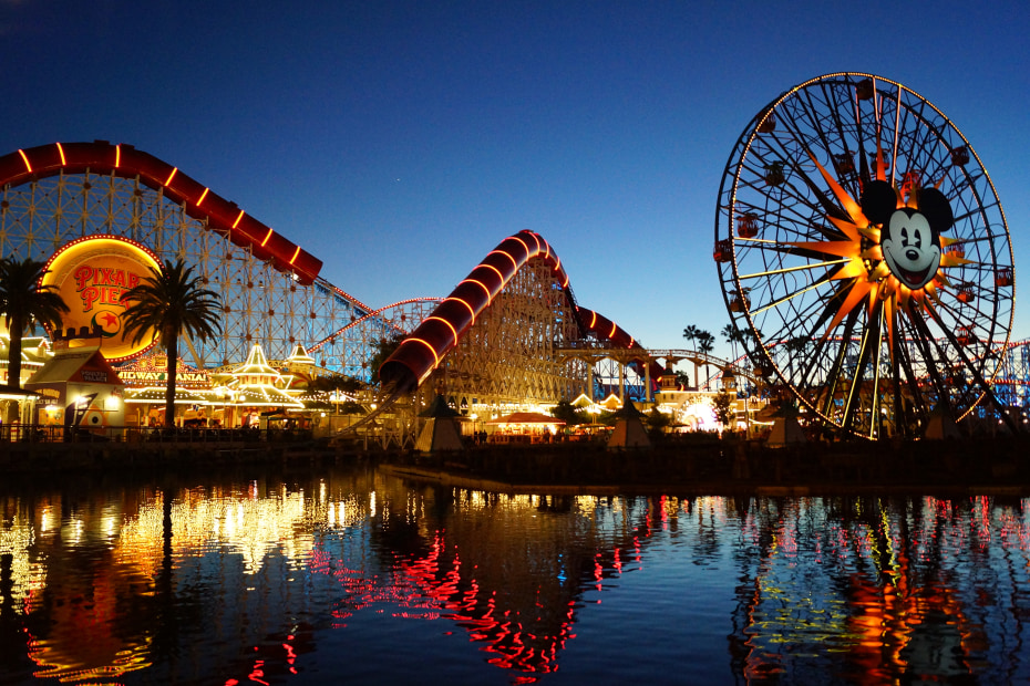 Picture of the view of Pixar Pier all lit up at night from the Lamplight Lounge with the water in the foreground