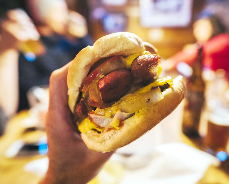 handful of burger held up for a bite with sausage, onions, ketchup, mustard on bun at Shooting Star Saloon in Huntsville, Utah, picture 