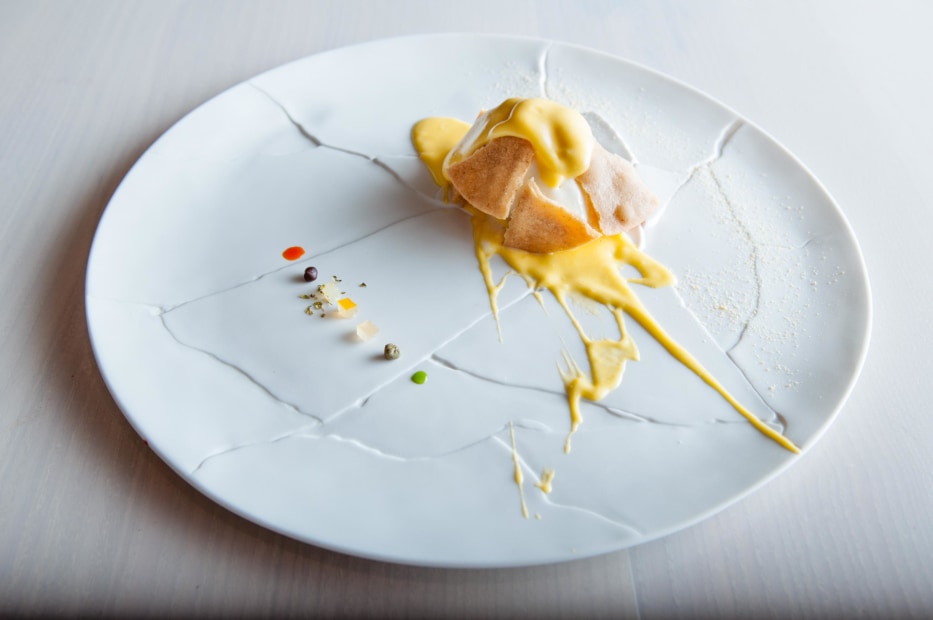 In Situ's Oops, I Dropped the Lemon Tart dessert, is an artful visual pun served with splattered sauce droplets on a white, craquelure plate in San Francisco, picture