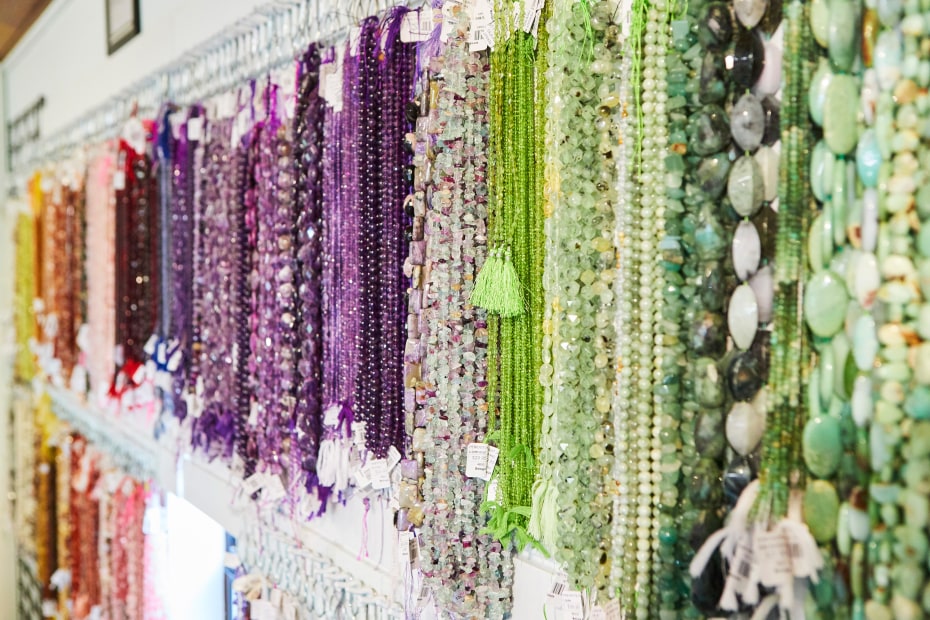 Photo of multicolored strands of beads for necklaces hanging on the wall