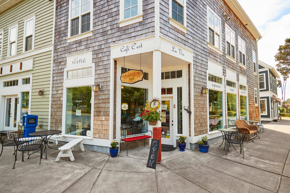 Photo of the exterior of a café with outdoor seating on a street corner. 