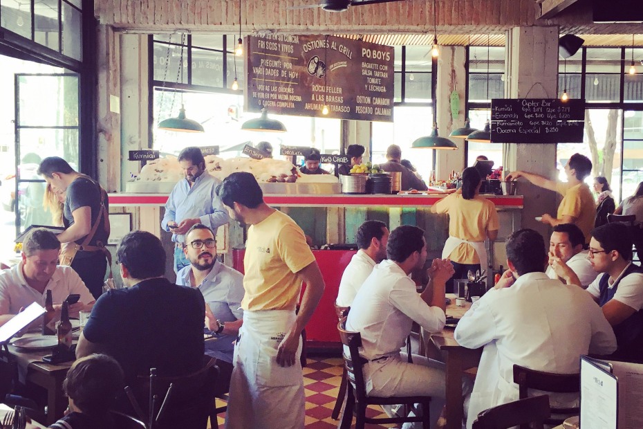 Crowded tables of patrons inside La Docena, an oyster bar in Mexico City, photo