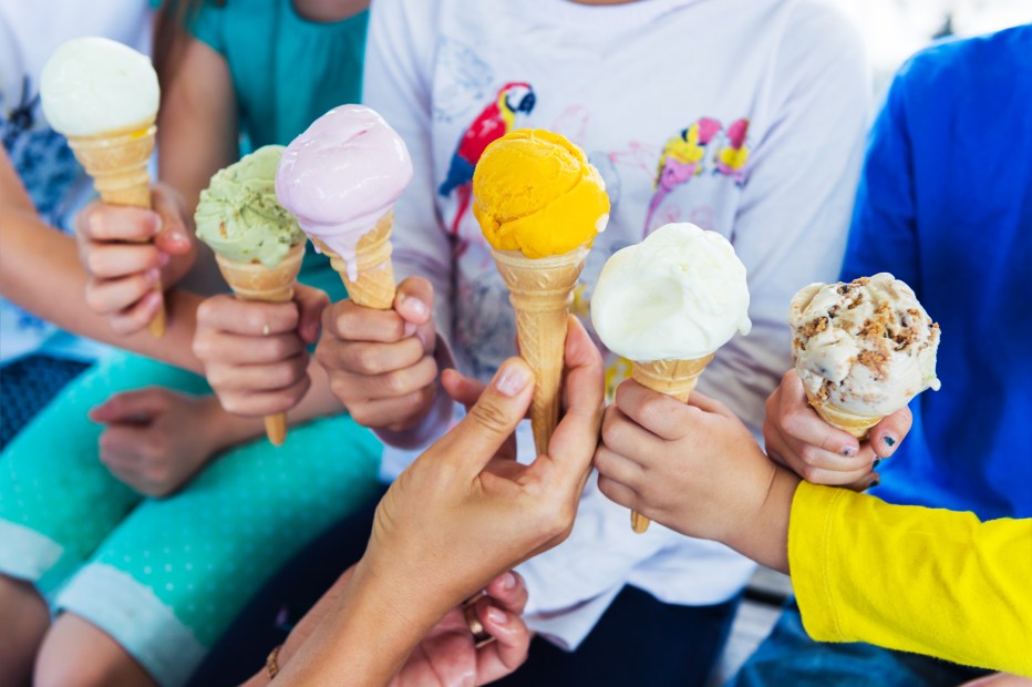 kids holding up ice cream cones topped with colorful scoops, picture