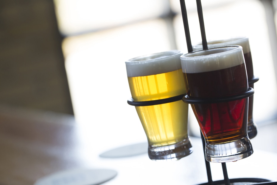 a trio of beers in a metal holder with light in the backgroune