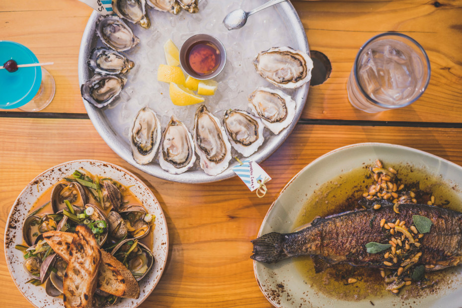 Platters of steamed clams, raw oysters, and roasted whole rainbow trout at Seattle's Westward, picture