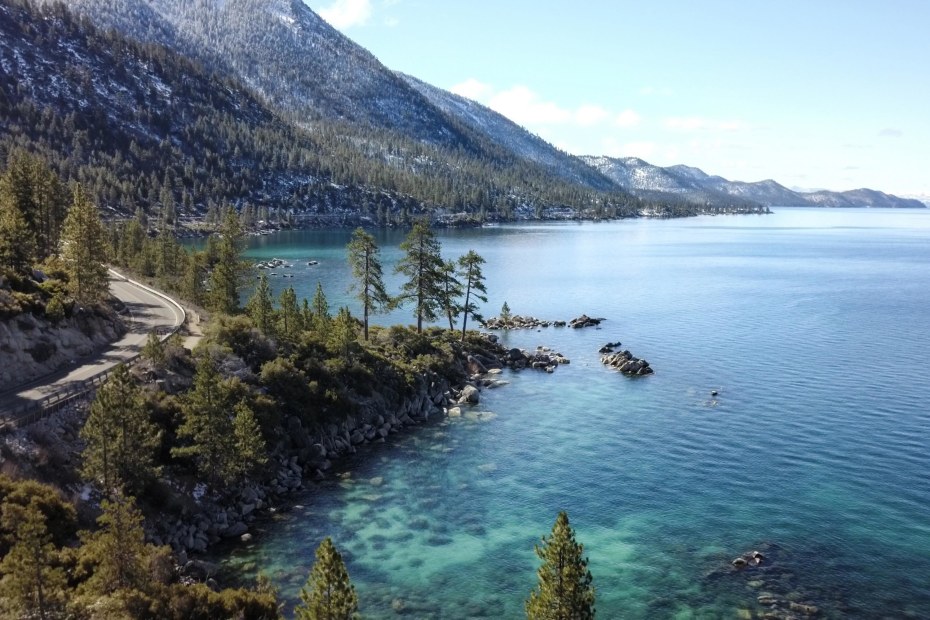 Lake Tahoe loop road along the edge of the lake with snow between the trees, image