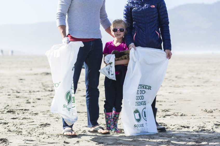 a family helps with beach cleanup, image