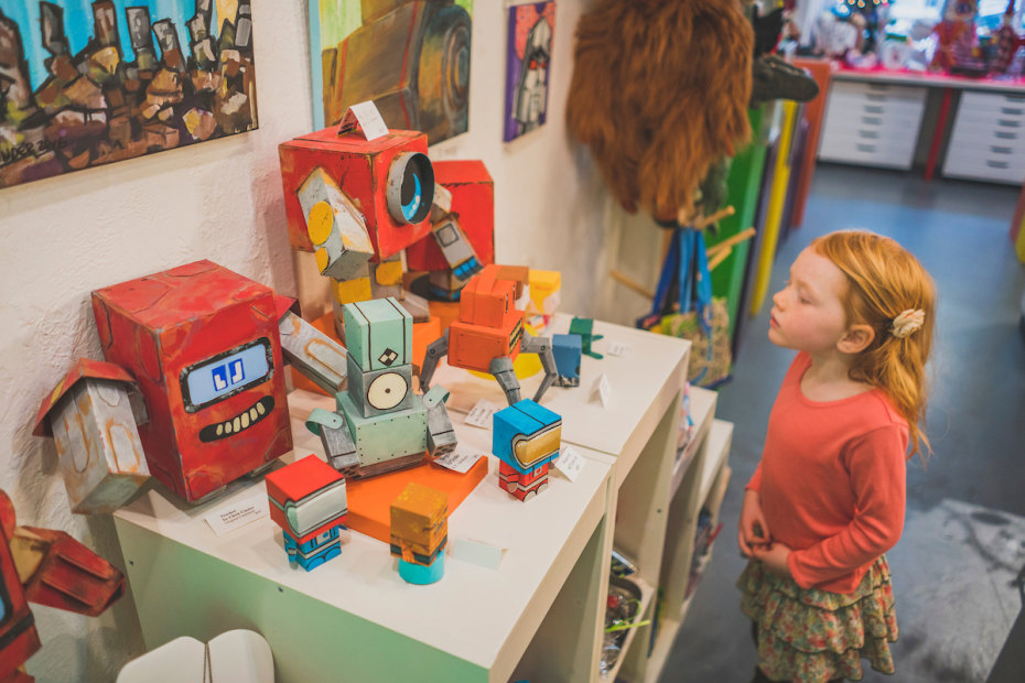 young girl peeks at handmade toys at Art of Toys in Sacramento, picture