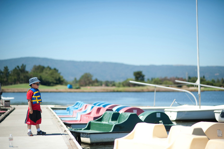 a young boy looks at a collection of pedal boats, picture