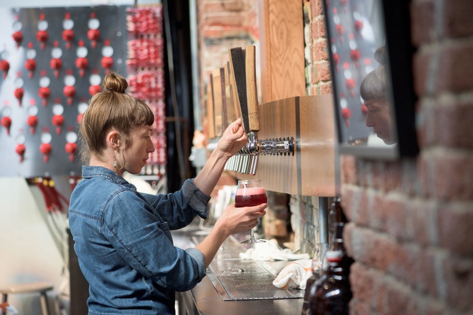 woman draws a beer from tap at Crooked Stave Artisan Beer Project in Denver, picture