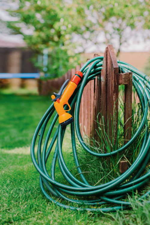A water hose coiled on a fence.