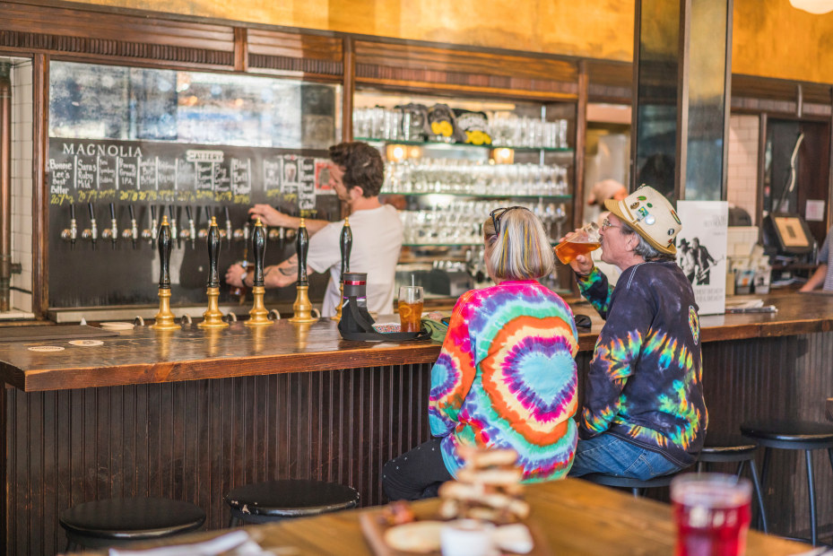 a couple sits at the bar drinking beer at magnolia, picture