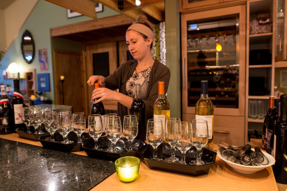 a woman pours wines behind the bar in the Ten Spoon tasting room