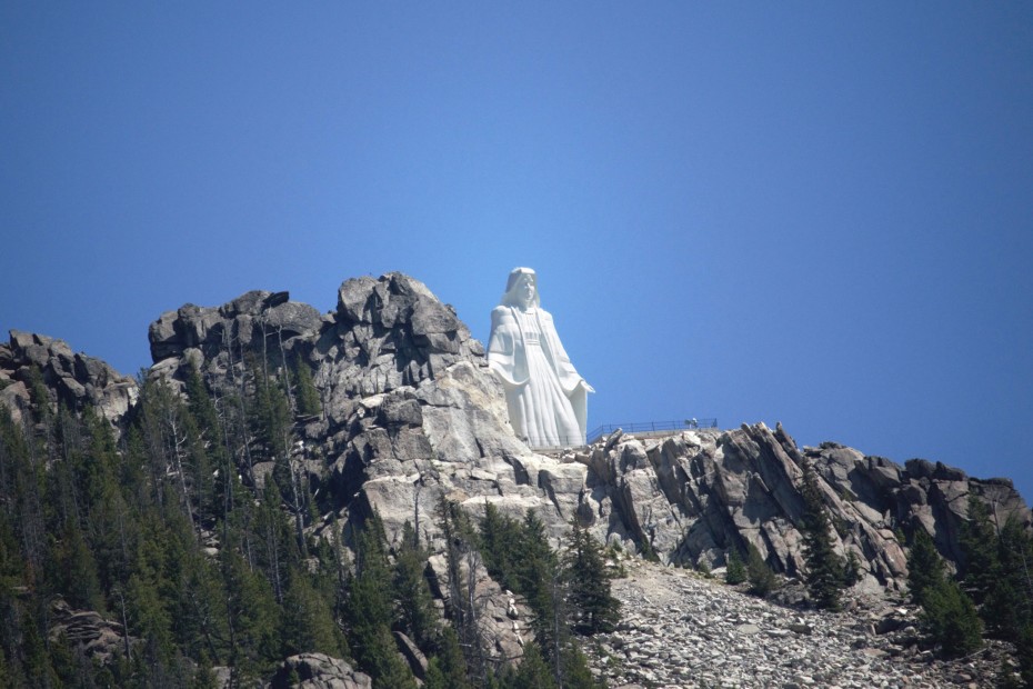 picture of a white statue of a woman on top of a rocky mountain