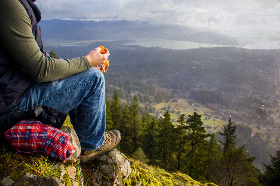 hiker pausing for snack takes in the panoramic view towards Nehalem Bay from Neahkahnie Mountain near Manzanita, Oregon, picture