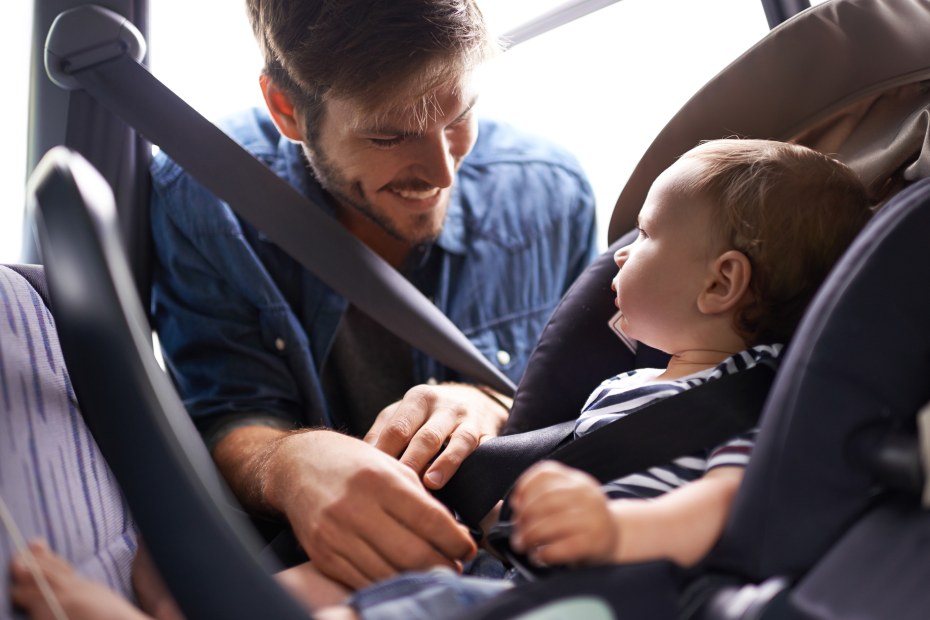 A father buckles his infant into a AAA inspected car seat