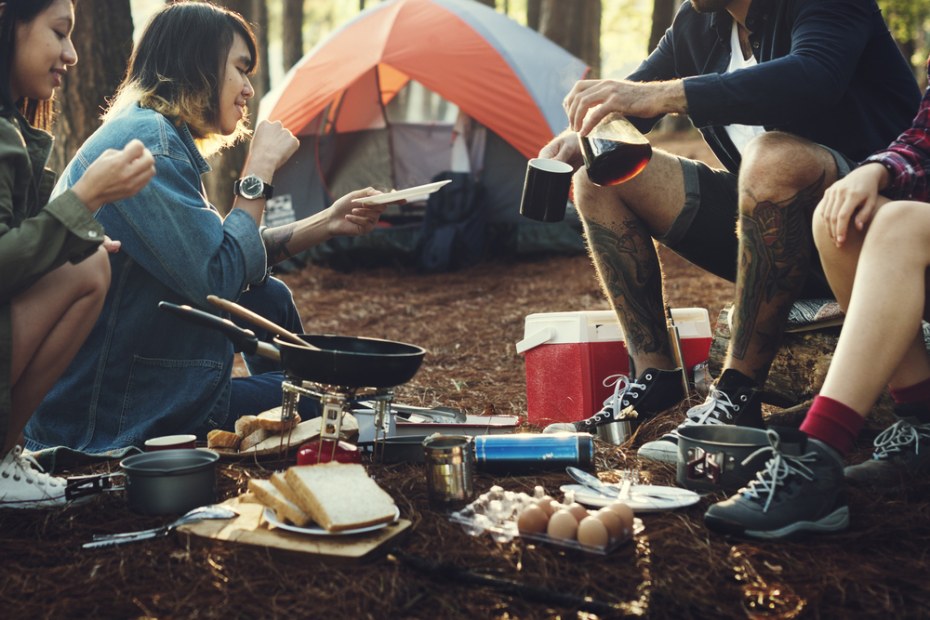 A group of friends sit around a borrowed camping stove to make breakfast