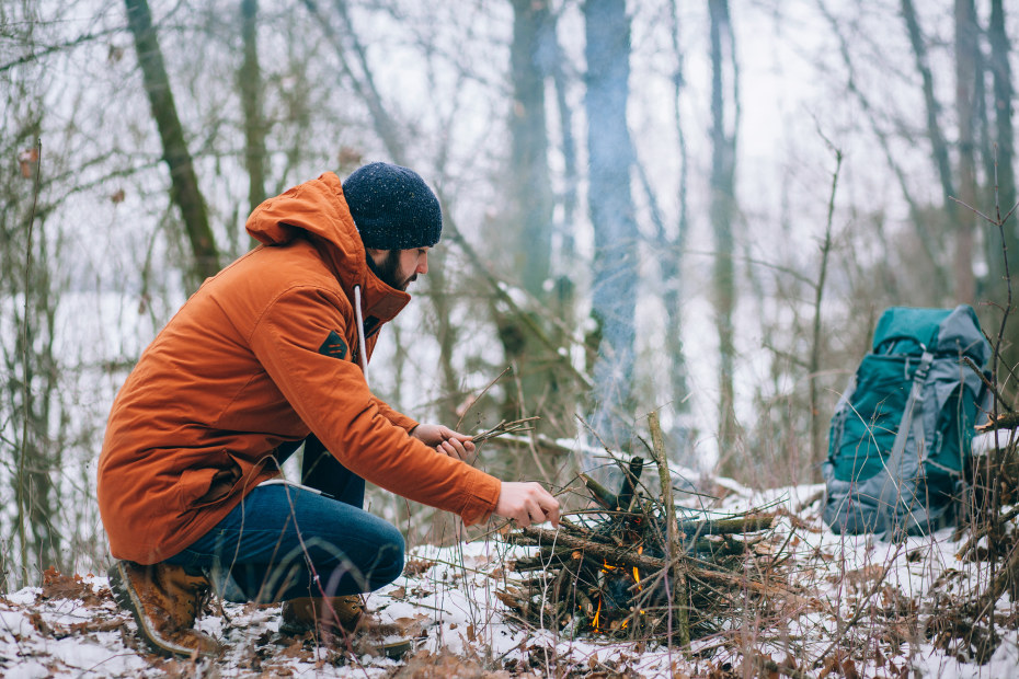 A man makes a fire in the snow, image