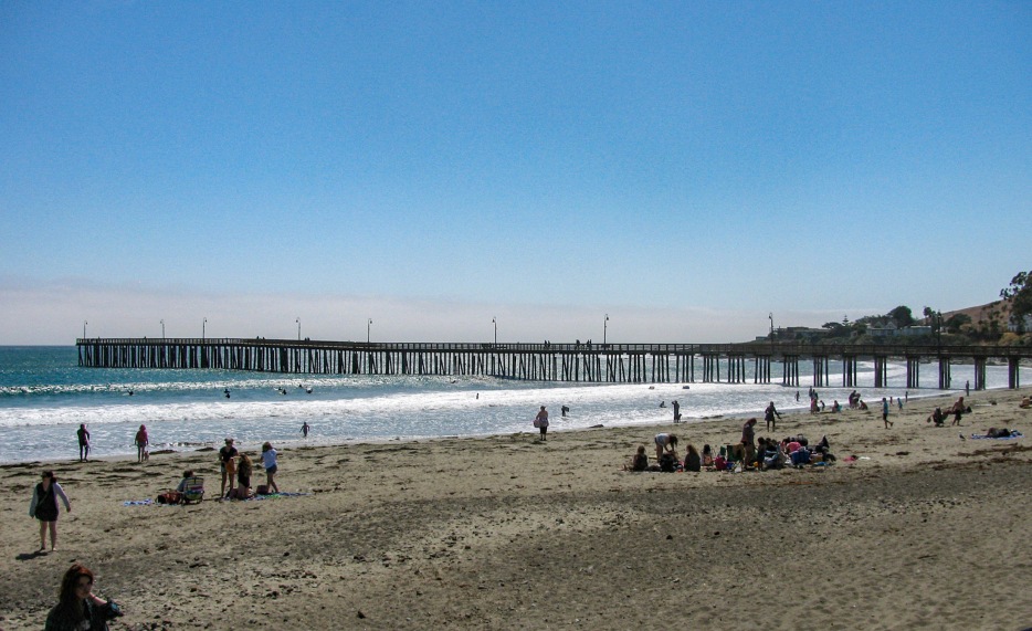 picture of people enjoying the beach with the Cayucos Pier in the background
