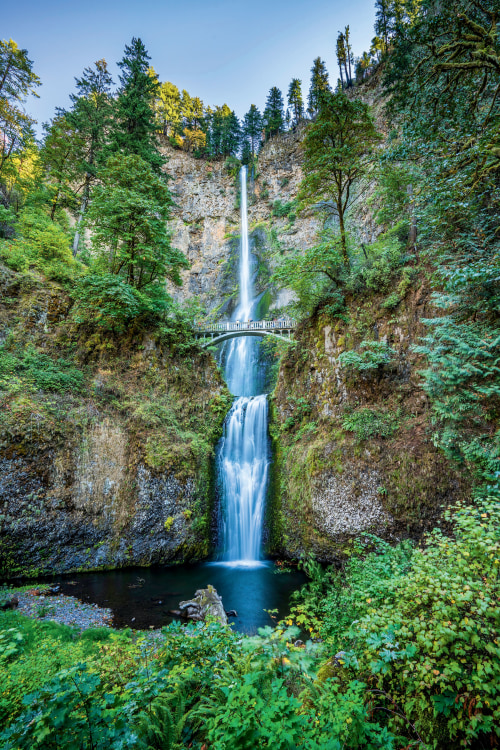 visitors admire the flowing Multnomah Falls from Benson Bridge in the Columbia River Gorge, near Troutdale, Oregon