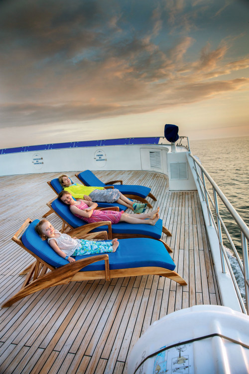 Mother and two daughters enjoy lounging on their deckchairs on a cruise