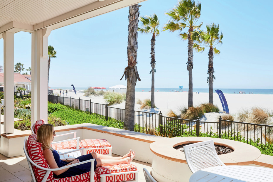 woman reclines in shade and sun on patio at Del's Beach Village in Coronado, California