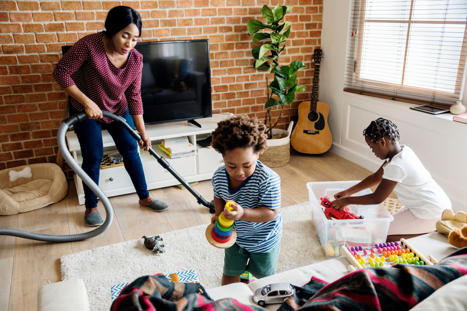 A mom and her two children clean up the living room together.