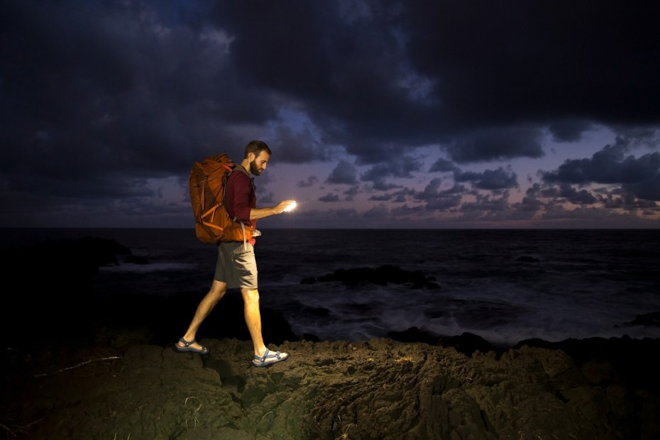 A hiker walks with a BioLite SunLite lantern lighting the way at night.