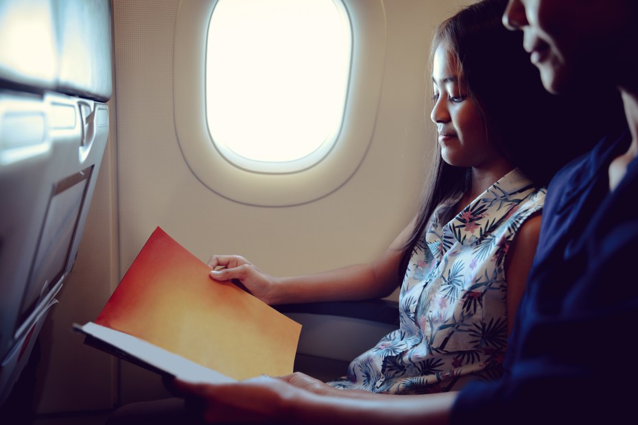 AAA Member reads with her school-aged daughter on an airplane.