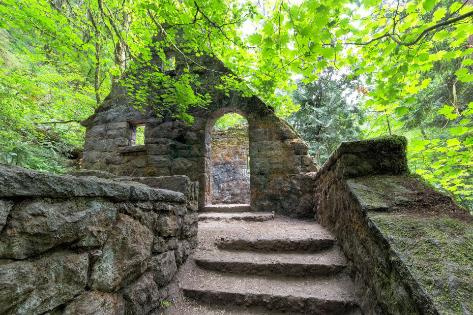 the crumbling stone wall of the Witch's Castle in Forest Park surrounded by green trees