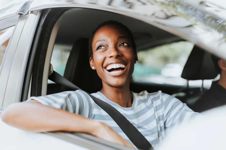 AAA Member smiles from the passenger seat of a rental car.