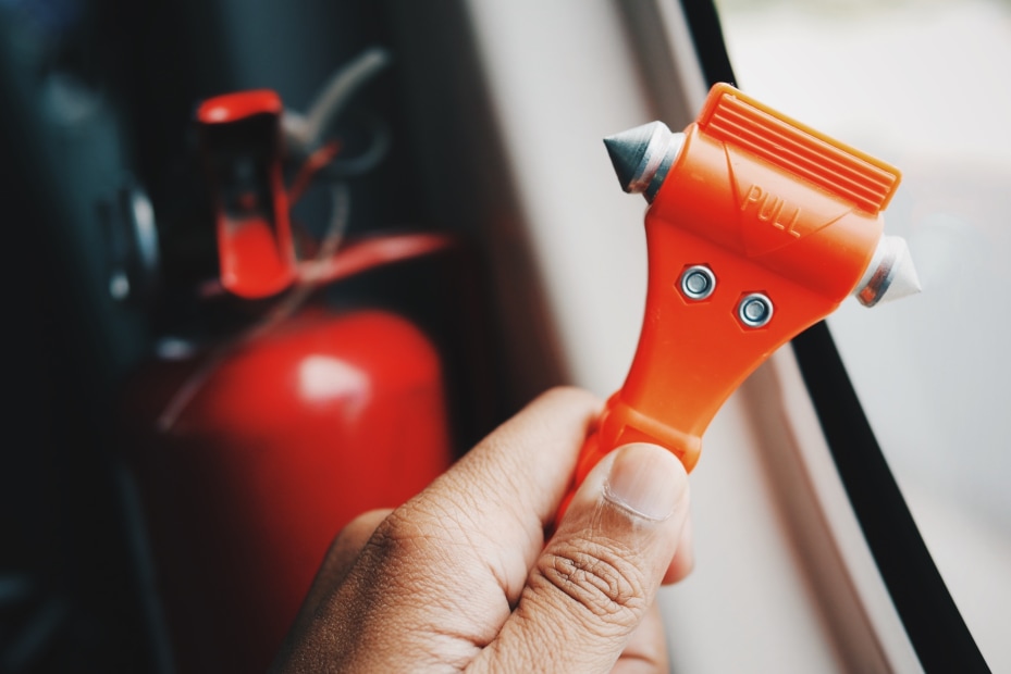 hand holding an orange, hammer-style vehicle escape tool