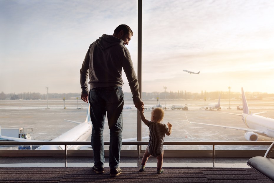 Father and baby watch planes take off at the airport.