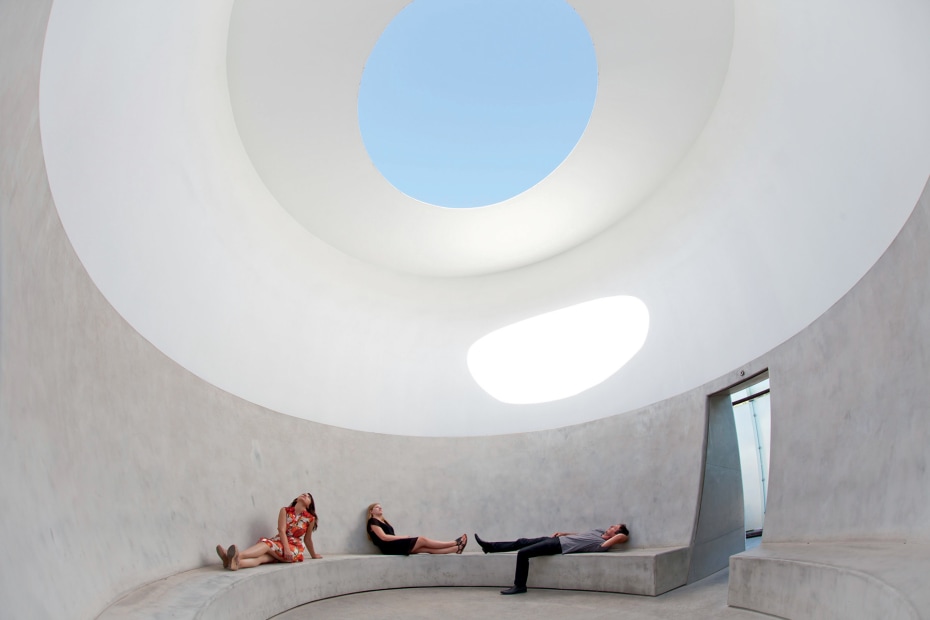 trio of visitors recline beneath James Turrell's "Knight Rise"—a large, elliptical hole in the roof—at Scottsdale Museum of Contemporary Art in Scottsdale, Arizona