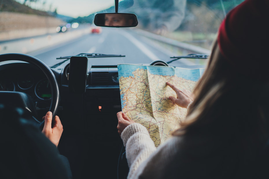 Car passenger navigates by paper map.