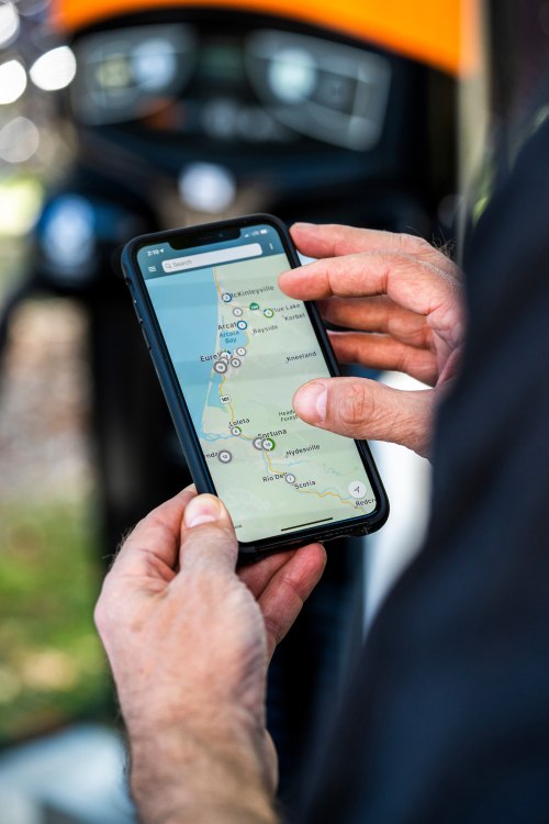 driver uses an electric vehicle charging station app to find a nearby charger.