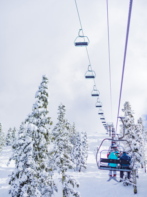 skiers on a ski lift on a cloudy day in Lake Tahoe, California.