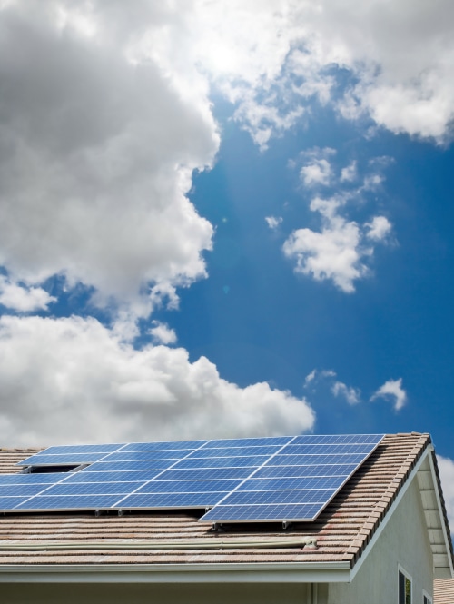 solar panels on pitched rooftop under partly cloudy and sunny sky