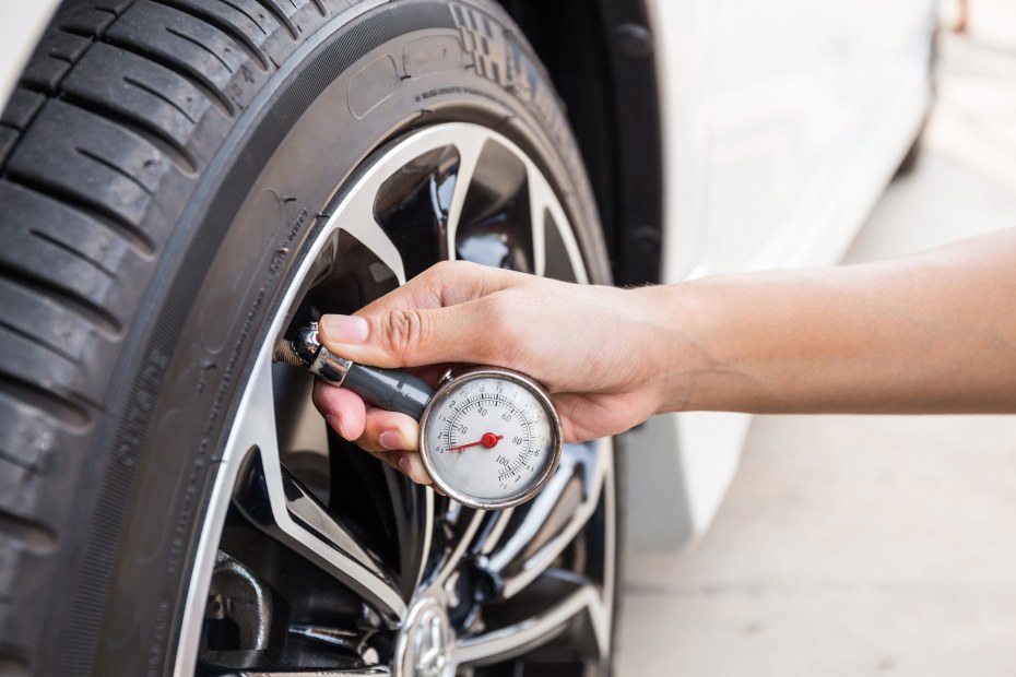 hand using tire pressure gauge on tire