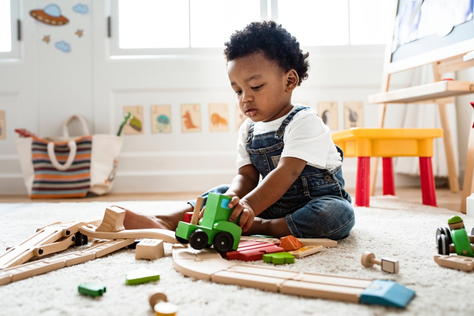 A toddler plays with a train set.