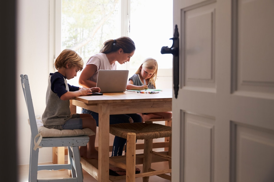 Mom does homework with kids at the kitchen table.