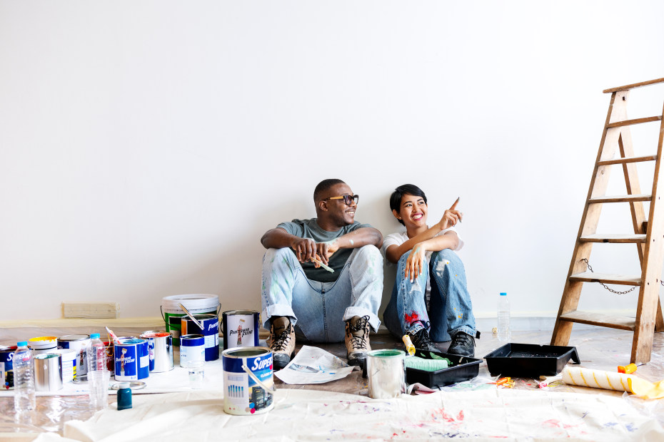 a couple paints a white room.