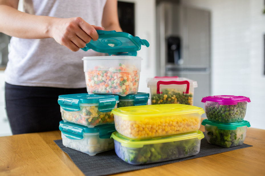 Woman prepares containers of mixed vegetables for refrigerator.