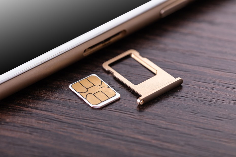 A SIM card next to a cell phone.