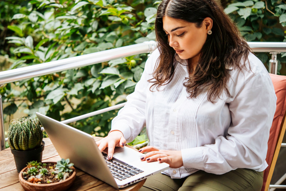 A woman uses her computer on the patio.