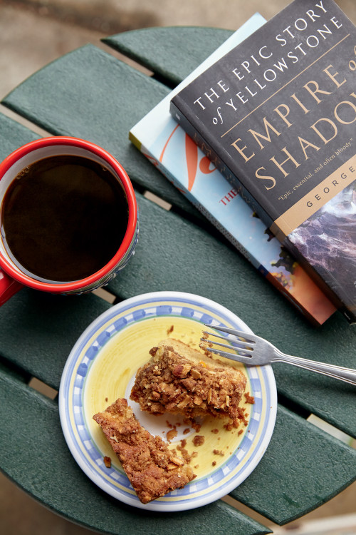 Table with cup of coffee, small dish with cake and fork, and books viewed from above, picture
