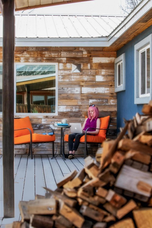 Kate Siber in pink wig, seated on her deck with laptop