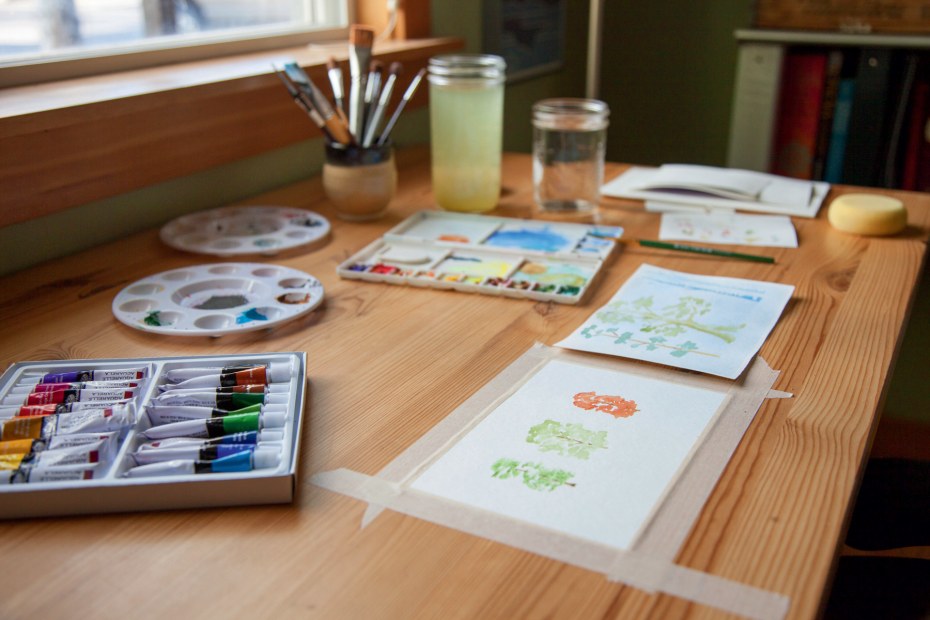 watercolors, brushes, small paintings and works in progress on table at Kate Silber's home, picture
