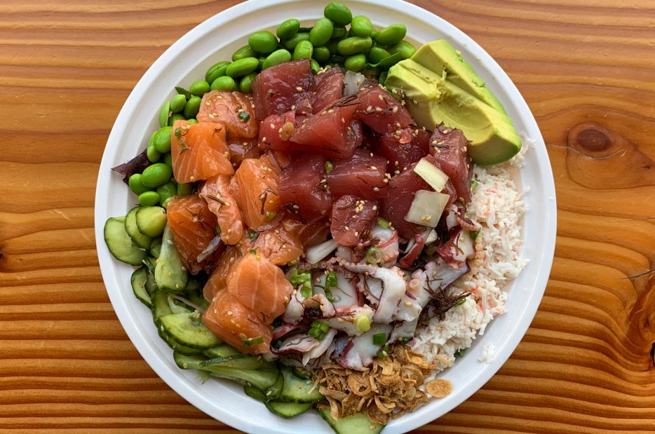 signature bowl of poké salad served with cubed ahi tuna, salmon, and tako (cooked octopus); circled by edamame, avocado, red onion, ginger, and cucumber from GoPoké in Seattle, Washington